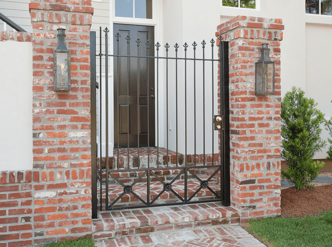 Custom brick entryway with wrought iron gate and lantern lighting in Cary, NC by Corner Solutions.