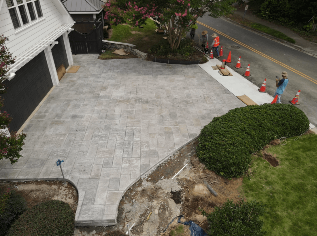 Custom driveway installation with patterned concrete pavers, curved edging, and integrated walkway leading to garage and front entry.