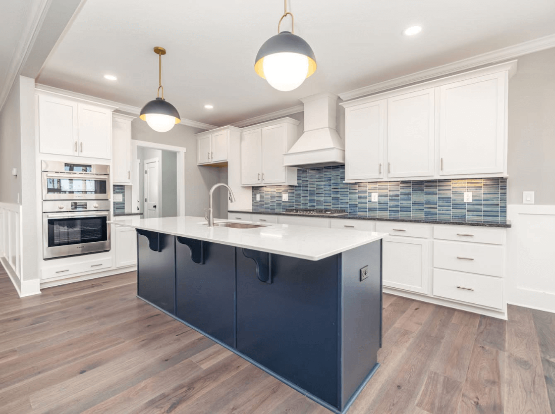 Cary NC kitchen renovation with white cabinetry, navy island, quartz countertops, engineered hardwood flooring, and modern tile backsplash.