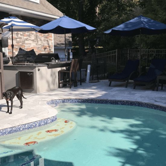 Backyard pool and patio renovation in Cary, NC with outdoor kitchen, lounge seating, and stone hardscaping by Corner Solutions.