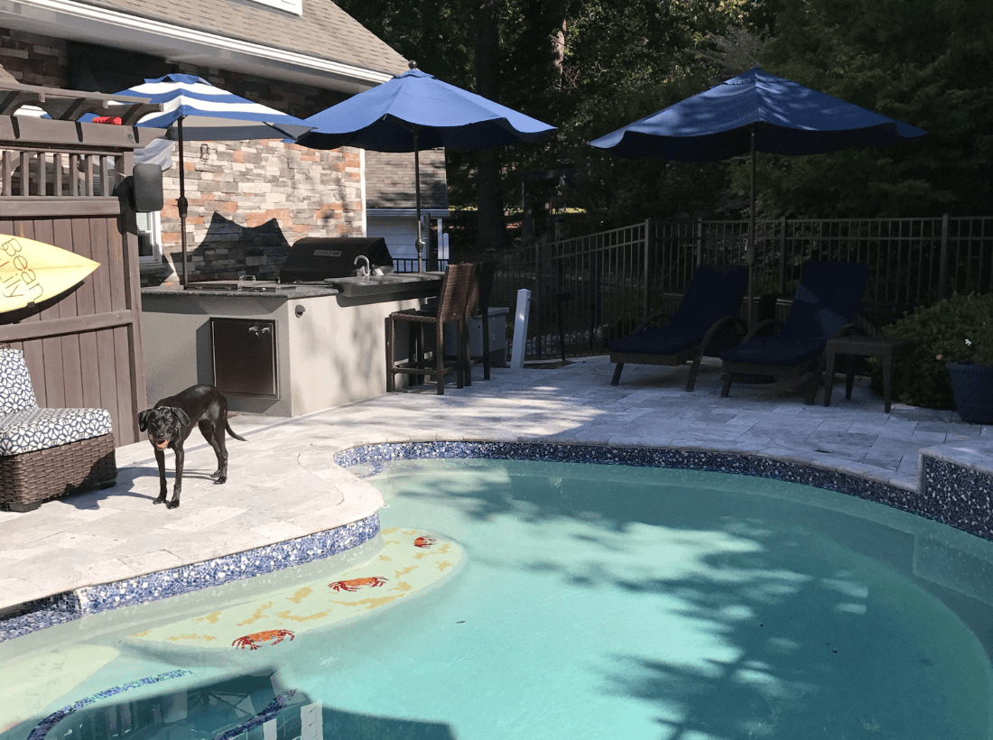 Backyard pool and patio renovation in Cary, NC with outdoor kitchen, lounge seating, and stone hardscaping by Corner Solutions.